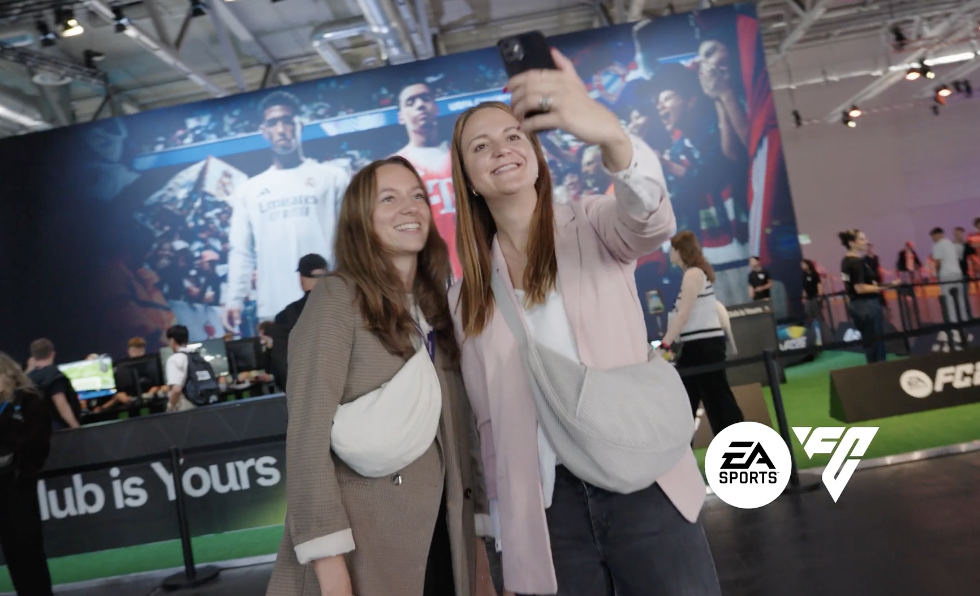 Besucherinnen machen ein Selfie vor der EA-Sports-FC-Bühne auf einem Event